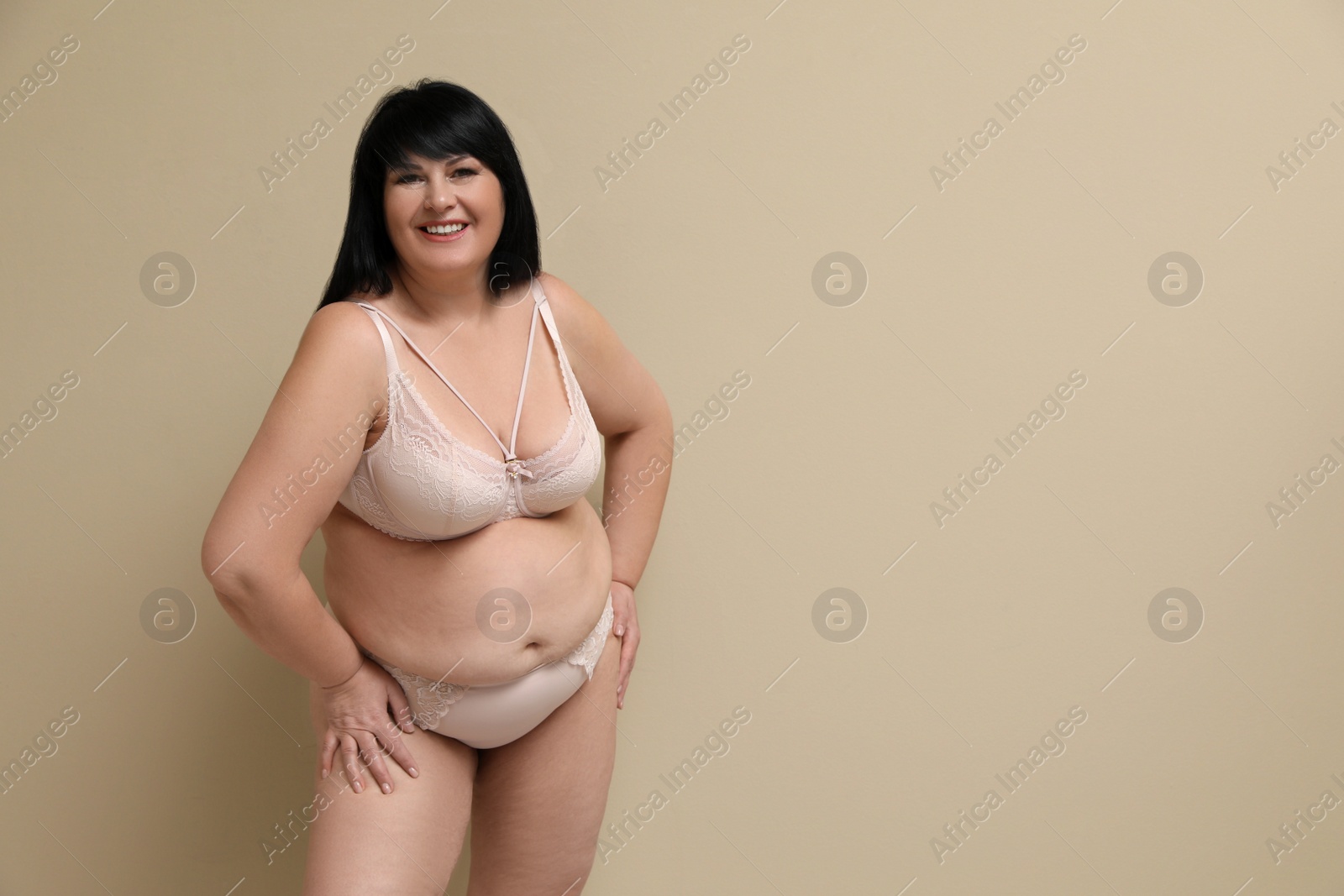 Photo of Beautiful overweight woman in underwear on beige background, space for text. Plus-size model