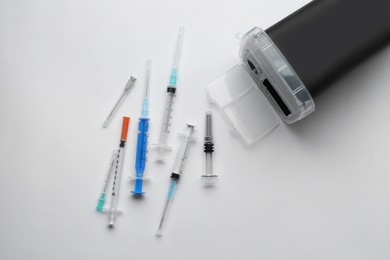 Photo of Disposable syringes with needles and sharps container on white background, top view