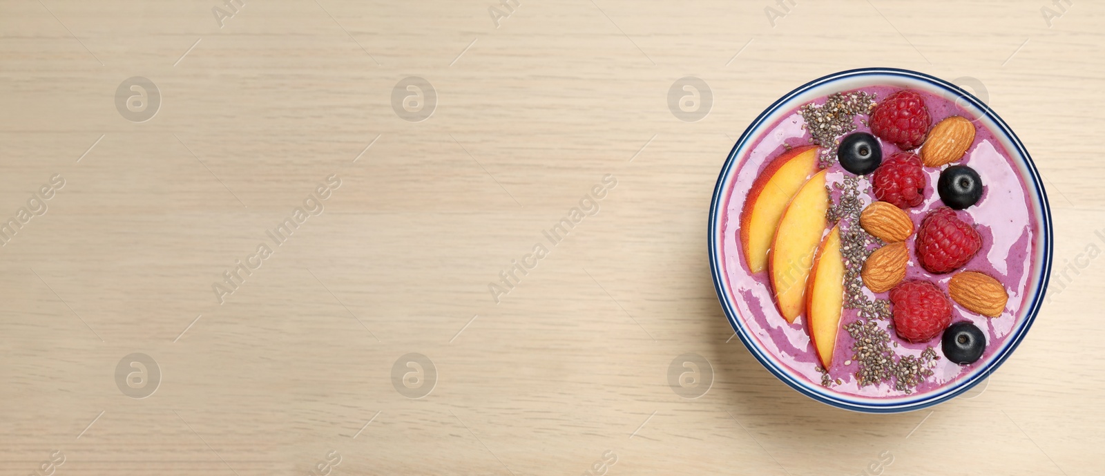 Delicious acai smoothie with fruits and almonds in bowl on wooden table, top view. Space for text Photo of Delicious acai smoothie with fruits and almonds in bowl on wooden table, top view. Space for text
