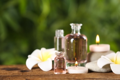 Photo of Beautiful spa composition with aroma oil and flowers on wooden table, closeup