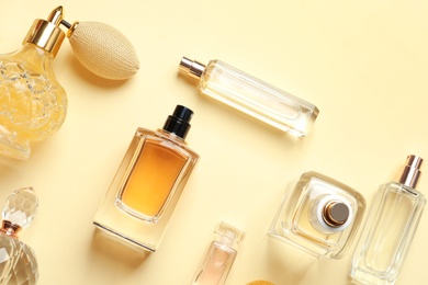 Photo of Flat lay composition with different perfume bottles on light yellow background