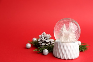 Photo of Beautiful snow globe and Christmas decor on red background, space for text