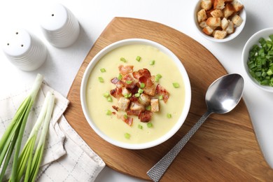 Photo of Tasty potato soup with bacon in bowl served on white table, flat lay