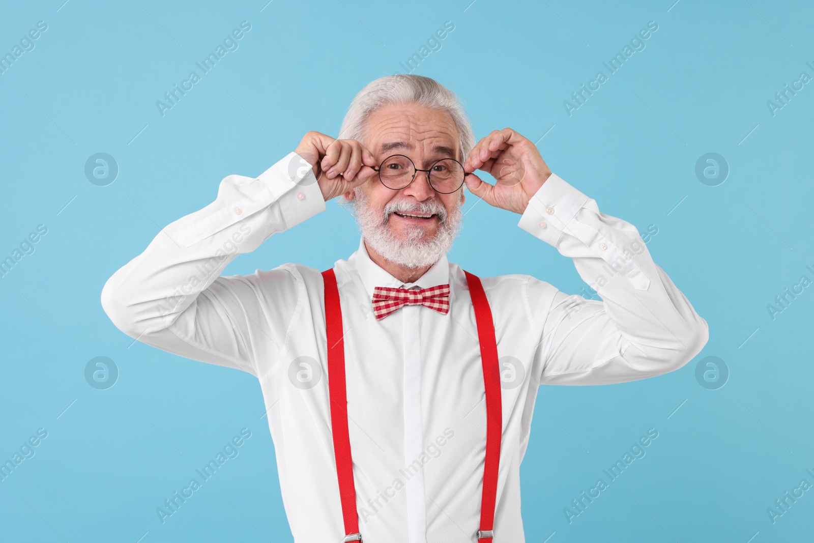 Photo of Portrait of stylish grandpa with glasses and bowtie on light blue background