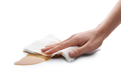 Photo of Woman wiping spilled coffee with paper napkin on white background, closeup