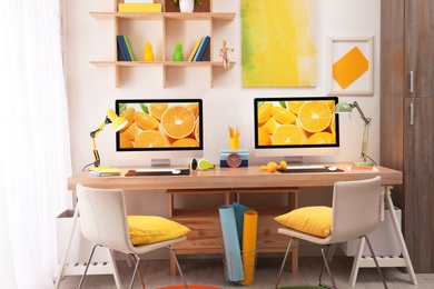 Photo of Modern workplace with large desk and computers in room. Stylish interior