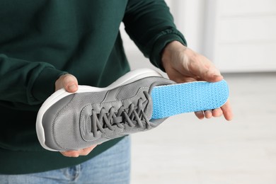 Photo of Man putting orthopedic insole into shoe indoors, closeup