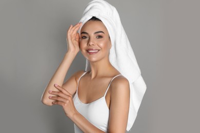 Beautiful young woman with towel on head against grey background