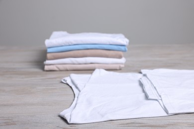 Photo of Sorting and organizing. Different folded and stacked clothes on light wooden table
