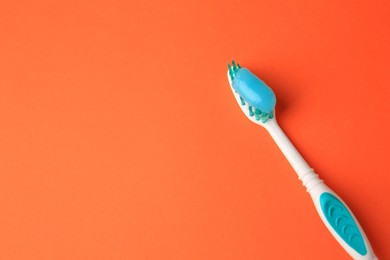 Brush and toothpaste on orange background, above view. Space for text