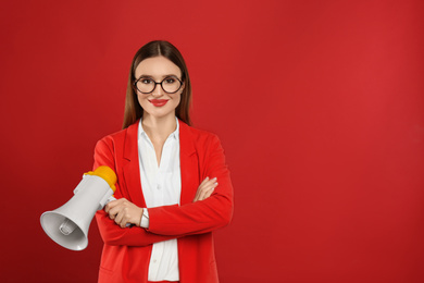 Photo of Young woman with megaphone on red background. Space for text