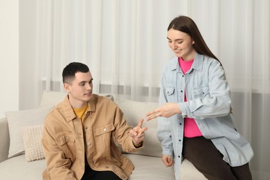 Photo of Happy people playing rock, paper and scissors in room