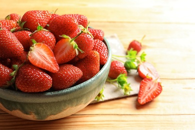 Bowl with fresh ripe strawberries on wooden table