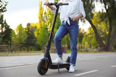 Photo of Woman with modern electric kick scooter in park, closeup