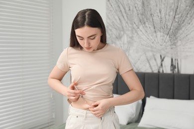 Photo of Diabetes. Woman making insulin injection into her belly in bedroom