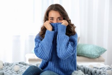 Photo of Portrait of young beautiful woman in warm sweater at home