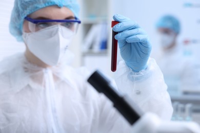 Photo of Scientist working with sample in test tube in laboratory, selective focus