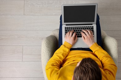 Photo of Man working with laptop in armchair, top view. Space for text