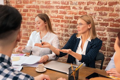 Photo of Businesswoman having meeting with her employees in office. Lady boss