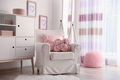 Photo of Pillows on light armchair in room interior. Unusual cushion design