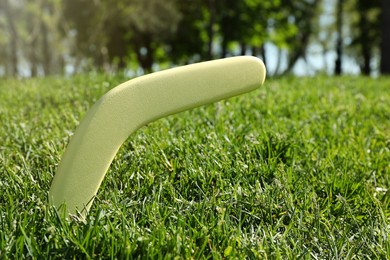 Photo of Yellow wooden boomerang in green grass outdoors