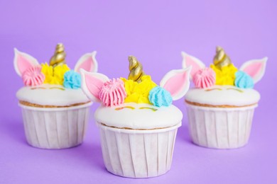Photo of Cute sweet unicorn cupcakes on violet background