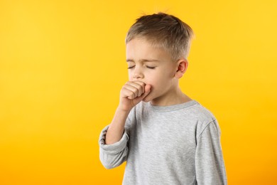 Photo of Sick boy coughing on yellow background. Cold symptoms