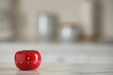 Photo of Kitchen timer in shape of tomato on white table against blurred background. Space for text