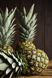 Photo of Fresh ripe juicy pineapples on wooden table, closeup