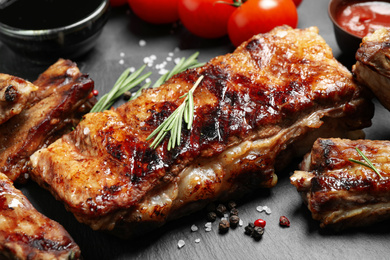 Photo of Delicious grilled ribs on slate board, closeup