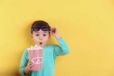 Photo of Cute little boy with popcorn and glasses on color background. Space for text
