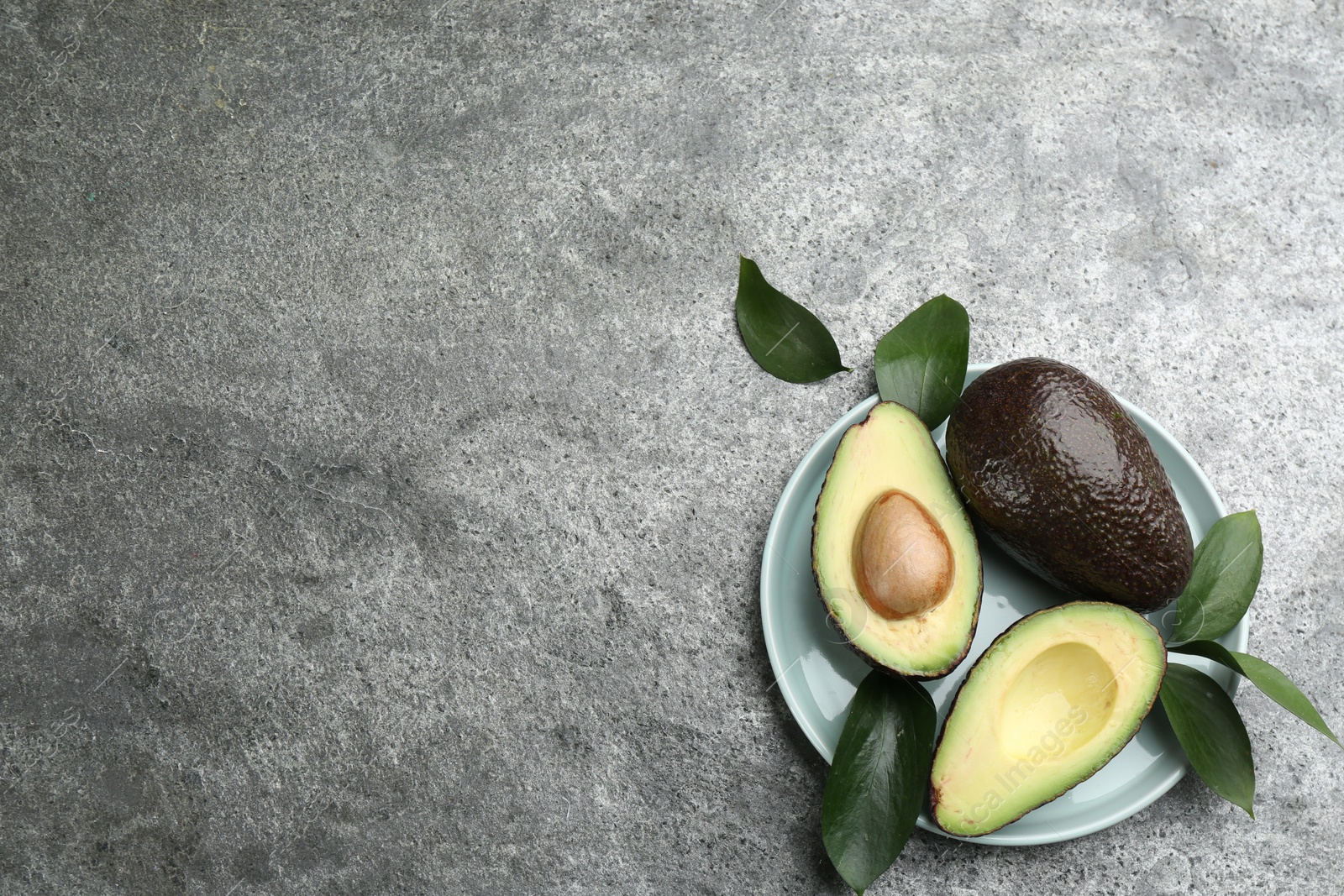 Photo of Whole and cut avocados on grey table, flat lay. Space for text