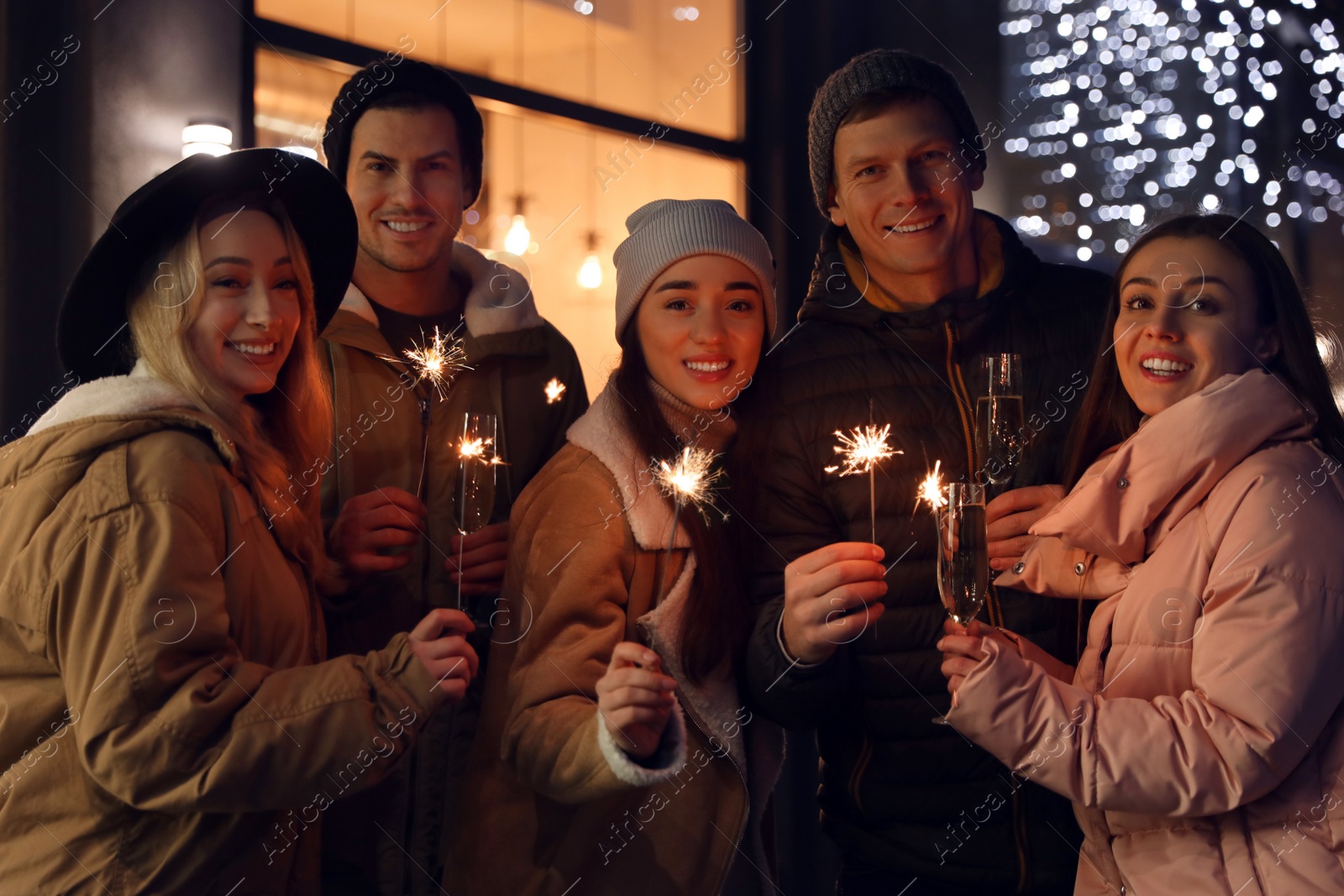 Photo of Group of happy friends with sparklers and champagne at winter fair
