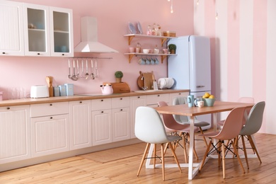 Stylish pink kitchen interior with dining table and chairs