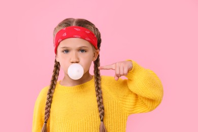 Photo of Girl blowing bubble gum on pink background
