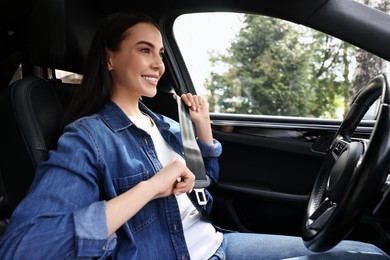 Photo of Woman fastening safety seat belt inside modern car