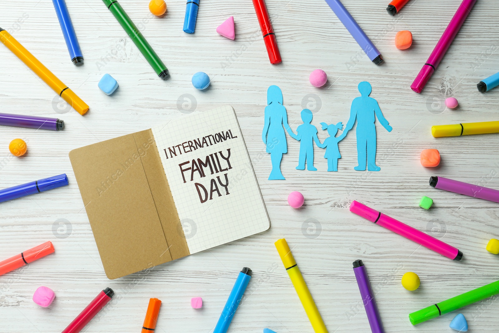 Photo of Happy Family Day. Flat lay composition with paper parents and their children near notebook on white wooden table