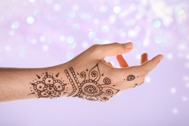 Image of Woman with henna tattoo on hand against blurred lights, bokeh effect