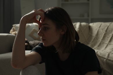 Photo of Sad young woman near sofa at home