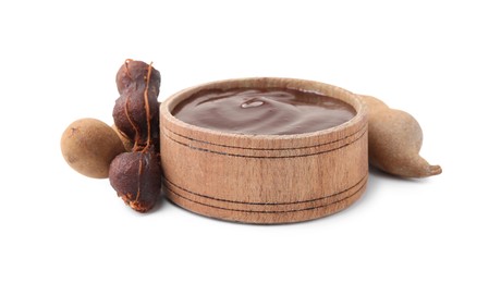 Photo of Bowl of tamarind sauce and fresh pods isolated on white