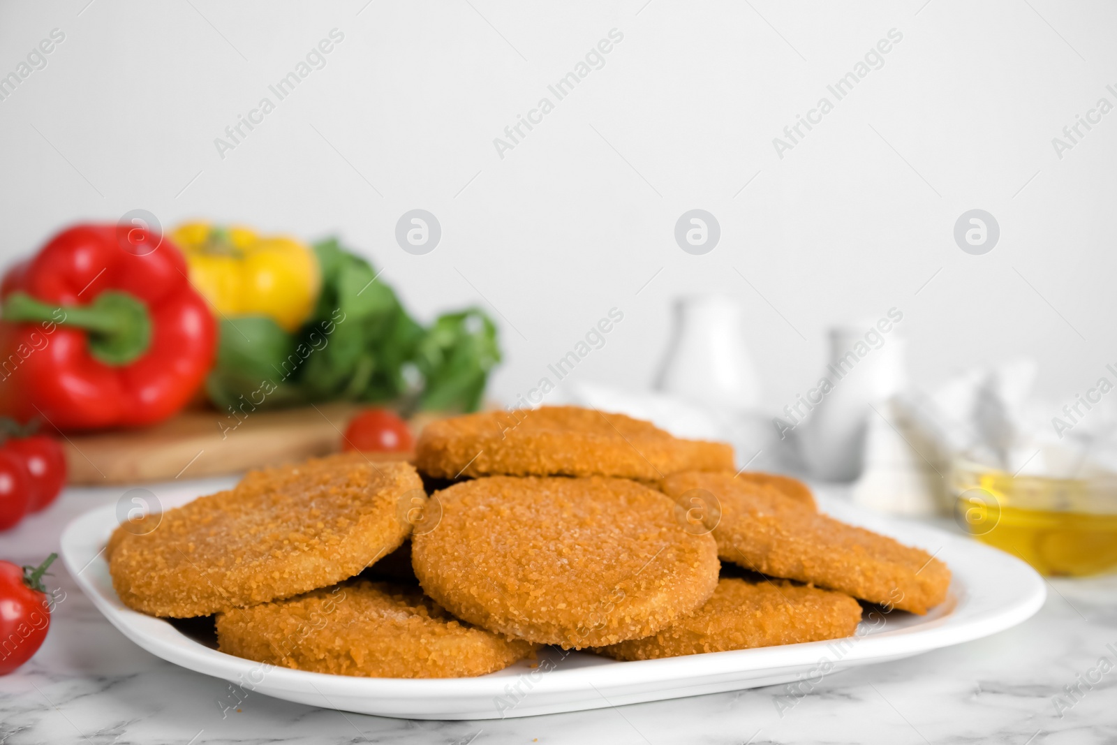 Photo of Delicious fried breaded cutlets on white marble table
