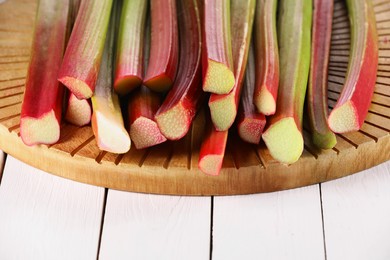 Photo of Many cut rhubarb stalks on white wooden table, closeup