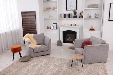 Photo of Comfortable armchairs, fireplace and shelves in living room. Interior design