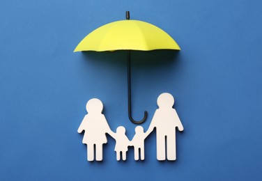 Photo of Mini umbrella and family figure on blue background, flat lay