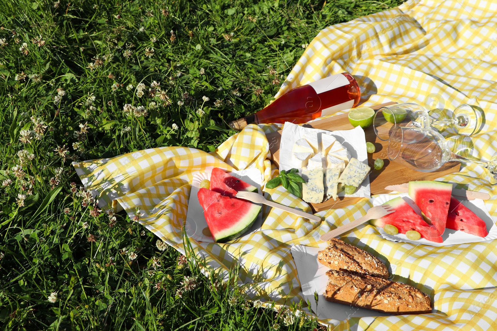 Photo of Picnic blanket with delicious food and wine on green grass outdoors