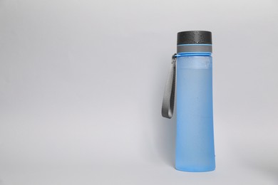 Photo of Stylish closed bottle with water drops on light grey background, space for text