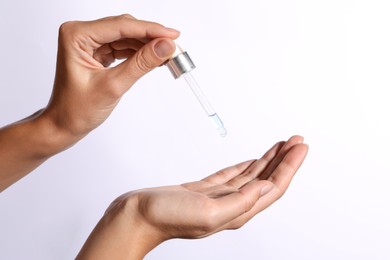 Photo of Woman applying cosmetic serum onto her hand on white background, closeup