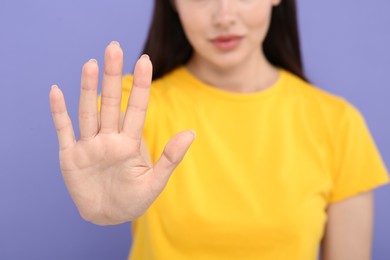 Photo of Woman showing stop gesture on violet background, closeup. Space for text