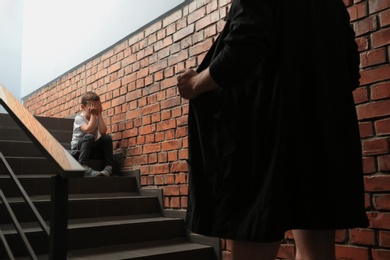 Photo of Male exhibitionist opening his coat in front of scared little boy indoors. Child in danger