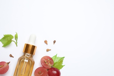 Photo of Composition with bottle of natural grape seed oil on white background, top view. Organic cosmetic